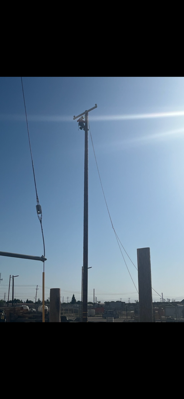 Silhouette climbing high on a single utility pole